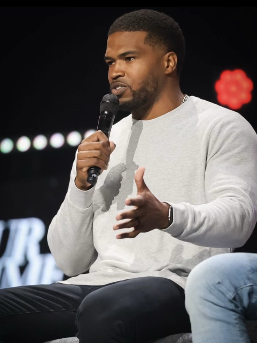 Justin Hilliard speaking on stage with a microphone.